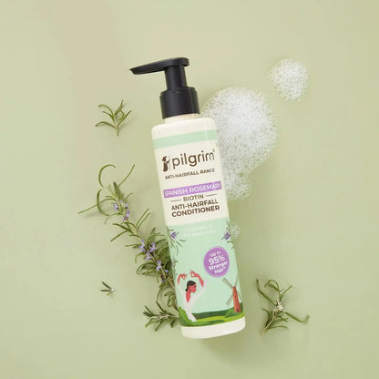 Pilgrim anti-hairfall conditioner bottle with rosemary leaves on a light green background